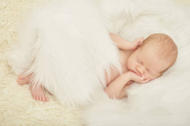 cute newborn girl sleeping on white fur closeup portrait