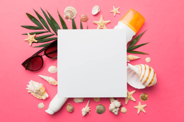istock Summer time concept with blank greeting card and blank white paper on colored background. Seashells from ocean shore in the shape of frame separated with space for text top view 1415567496