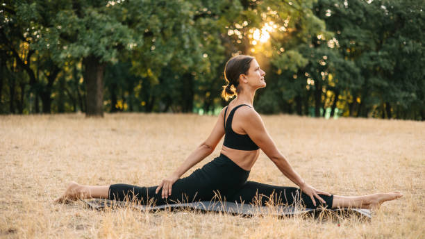 istock Yoga teacher doing the splits on a meadow at sunset 1415570384