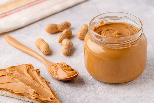 Peanut paste in an open jar and toast