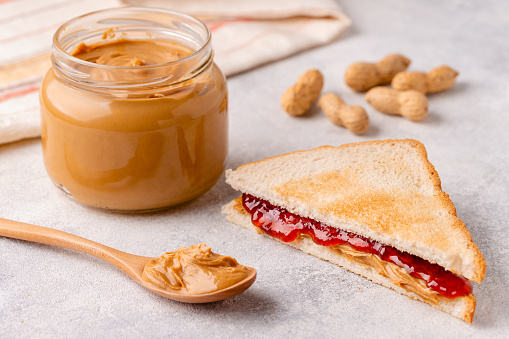Peanut paste in an open jar and toast