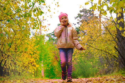 Little girl walking in the Autumn park, eating wild apples, Beautiful in nature. Happy time