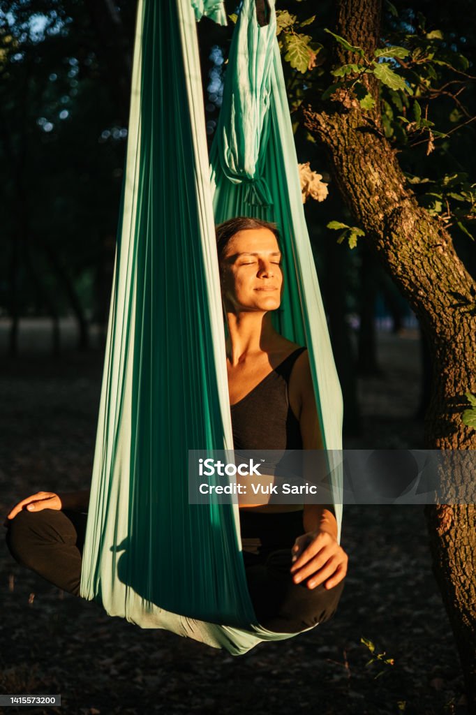 Aerial yoga techer resting in aerial silk A young yoga teacher sitting in aerial silk and enjoying sunset 30-34 Years Stock Photo