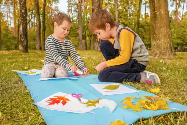 Photo of Diy art kid creative play learning outside school outdoor learning park school. Kids workshop children glue scissors art craft kids handmade autumn child art education nature creative autumn leaves