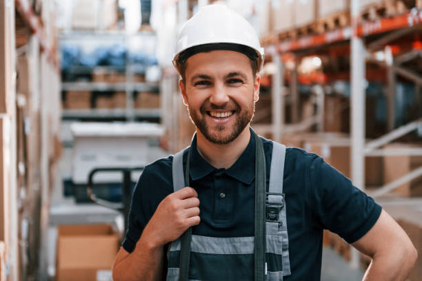 istock Smiling for the camera. Employee in uniform is working in the storage at daytime 1415574626