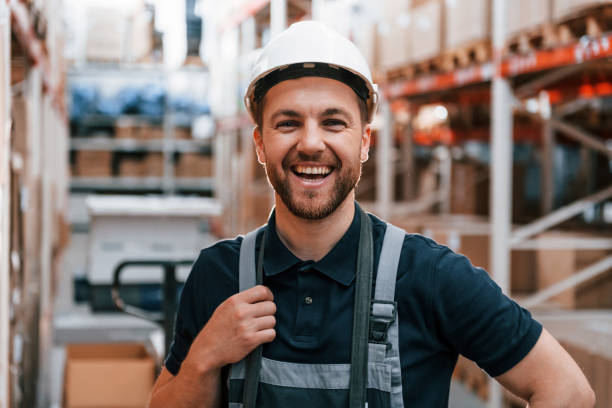 istock Smiling for the camera. Employee in uniform is working in the storage at daytime 1415574634