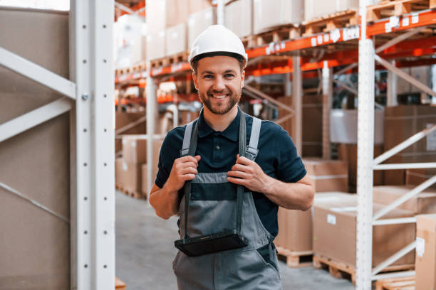 istock Smiling for the camera. Employee in uniform is working in the storage at daytime 1415574642