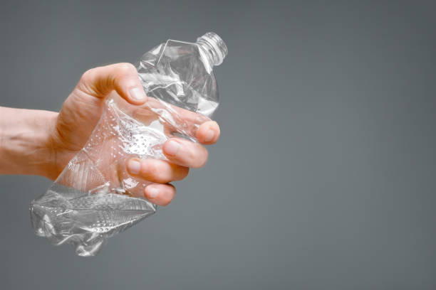 istock Crumpled bottle pet plastic resize or zero waste plastic hand recycling garbage crush. Raised hands holding crumpled plastic bottle hand squeeze bottle water plastic recycle reuse reduce waste concept 1415574727
