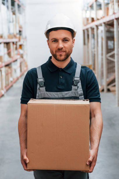 istock With delivery package in hands. Employee in uniform is working in the storage at daytime 1415574903