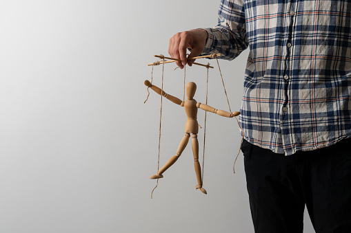 emploee holding a marionette wooden doll, manipulation concept