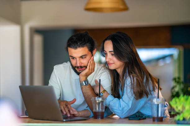 istock Young couple using laptop in a coffee shop 1415577824