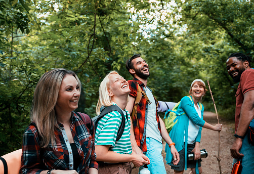 Smiling cheerful Multiethnic young hikers laughing in nature walk in woods. Copy space
