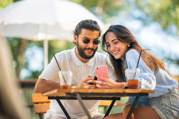 Young couple using mobile phone at coffee shop stock photo
