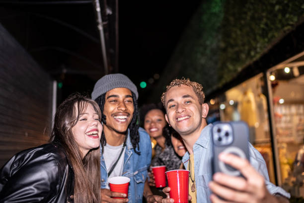 amigos felizes tirando uma selfie ao ar livre à noite - latin american and hispanic ethnicity flash - fotografias e filmes do acervo