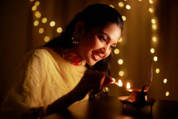 Beautiful Hindu Indian young women lightening Deepa on Diwali day.