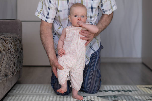 istock Little toddler infant child make first steps at parent support and care 1415580085