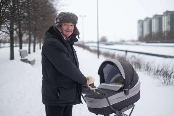 istock Grandfather walking with a baby stroller on snowy winter day 1415580911