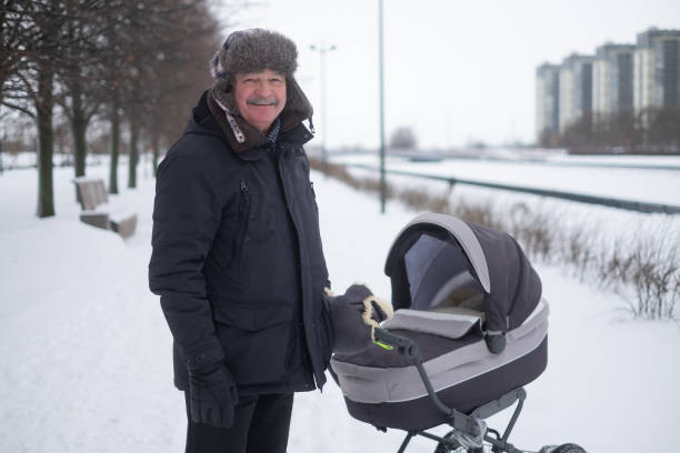 istock Grandfather walking with a baby stroller on snowy winter day 1415580975
