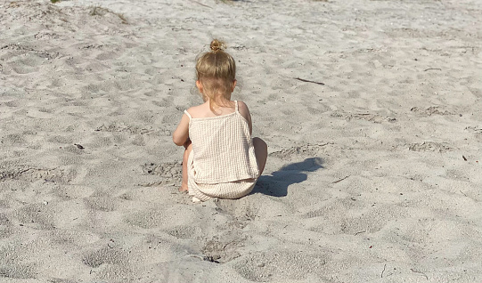 Toddler girl playing in the sand on a warm summer day