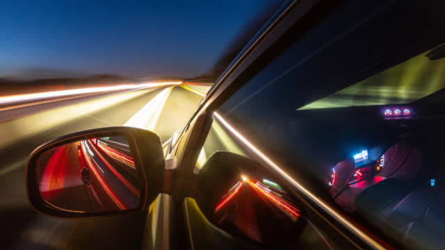 Driving at night on highway, illuminated by blurred street and car lights