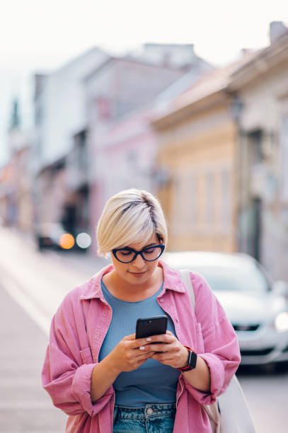 istock Young plus size woman using smartphone while walking in the city. 1415585915