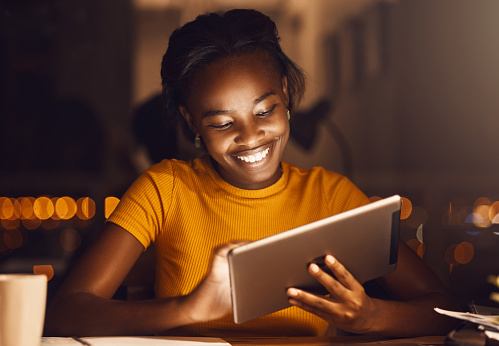 Estudiante hermosa, feliz y sonriente que usa una tableta para navegar por Internet, investigar o desplazarse en las redes sociales mientras trabaja en casa. Chica alegre, joven y alegre buscando en la web photo
