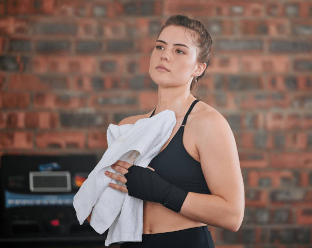 istock Sweaty, active sports woman taking break from a training workout session, exercising or boxing in gym with sportswear. Strong, healthy and athletic woman wiping sweat with towel at a wellness center 1415596727
