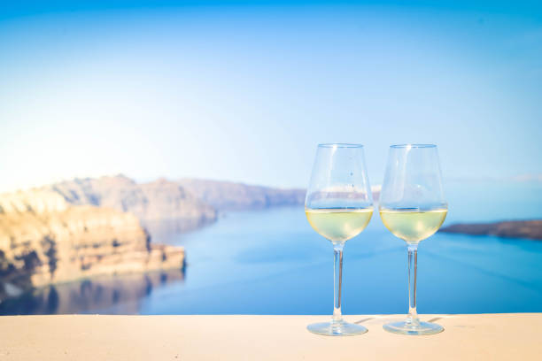 two glasses of wine over sunny background of Santorini island caldera