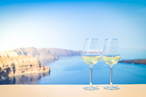 two glasses of wine over sunny background of Santorini island caldera