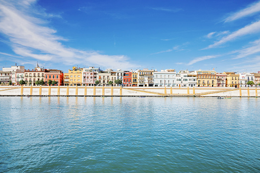 8th June, 2022 - Brightly coloured town houses, shops, bars and villas of Calle Betis along the riverside promenade of the Triana district along the Embankment of the Guadalquivir River in the city of Seville, Andalusia, Spain on a sunny June day