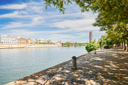 8th June, 2022 - Brightly coloured town houses, shops, bars and villas of Calle Betis along the riverside promenade of the Triana district along the Embankment of the Guadalquivir River in the city of Seville, Andalusia, Spain on a sunny June day
