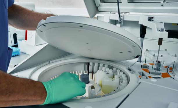 istock Diagnostic laboratory scientist in protective gloves working with biochemical automatic blood analyzer, close-up 1415600774
