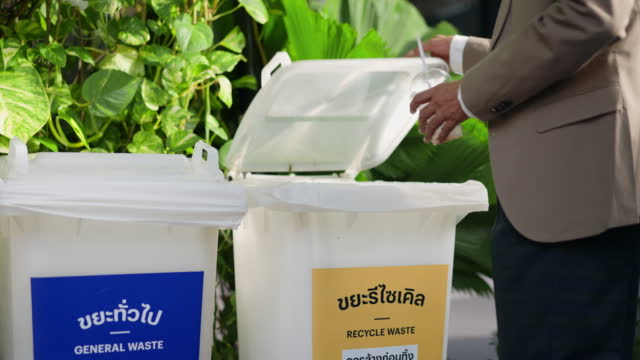 Man puts plastic glasses in a recycling bin.
