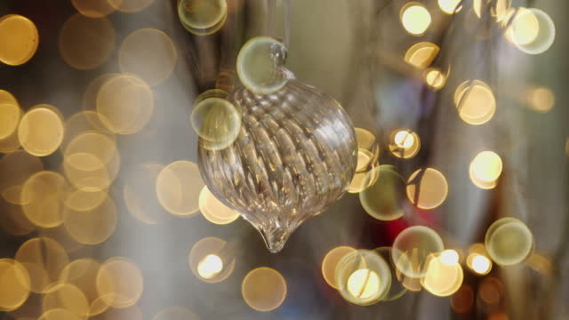 4K Stock video of Christmas bauble surrounded by out of focus Christmas lighting.