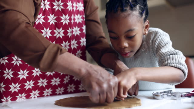 Grandmother making Christmas gingerbread cookies with her granddaughter