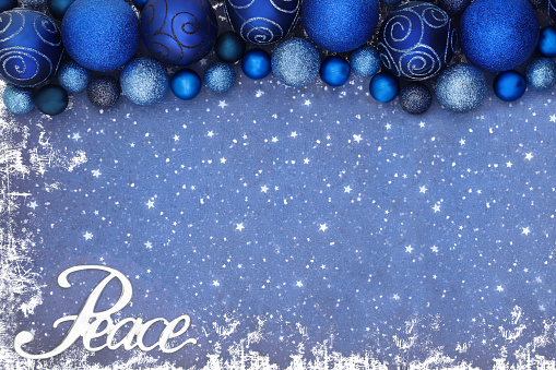 Christmas peace sign background border with blue sparkling glitter tree bauble decorations on grunge. Creative festive peace on earth concept for the Xmas holiday season.