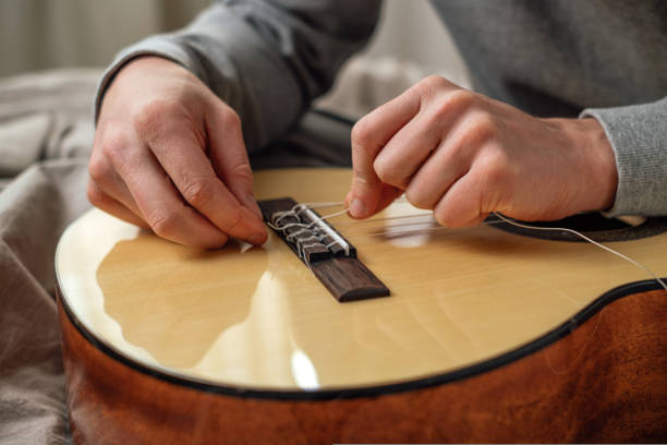 istock Hands of a young man changing the string on an acoustic guitar 1415603563
