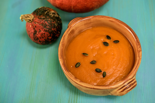 Fresh Pumpkin Soup with Pumpkin Seeds on Blue Wooden Background