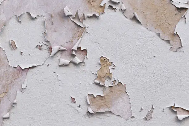 Photo of Closeup of badly fixed building facade wall covered with cracks in stucco and paint.