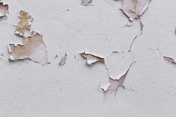 Closeup of badly fixed building facade wall covered with cracks in stucco and paint.