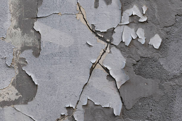 istock Closeup of badly fixed building facade wall covered with cracks in stucco and paint. 1415606773