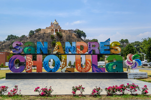 Cholula, Puebla, Mexico - APRIL 12, 2022: Colorful Sign for San Andres de Cholula in front of the Giant Pyramid of Cholula and Santuario de la Virgen de los Remedios on April 12 in Cholula, Mexico
