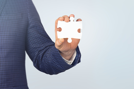 Businessman holding white puzzle piece with copy space. Business concept