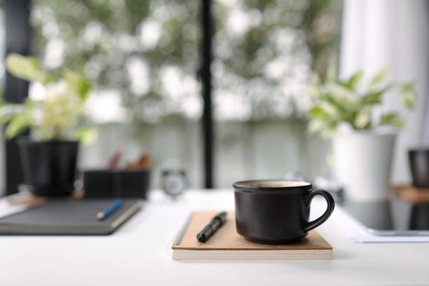 istock Black coffee cup and black pen and notebook on white table 1415608978
