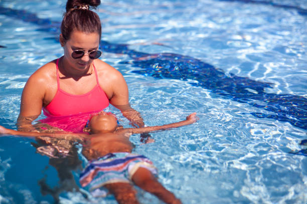 istock Swimming Instructor Teaching 3 year old how to Swim 1415610339