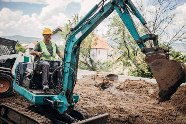 Workers wearing proper PPE operate a hydraulic excavator for trench digging