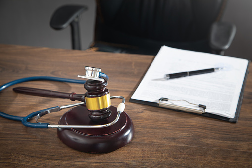 Judge gavel, documents and stethoscope on the wooden table.