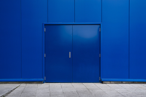 Blue industrial door on front of blue block modern warehouse.
