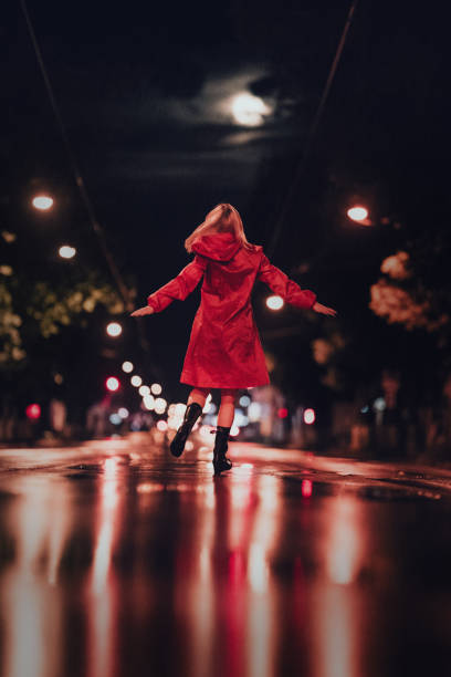 Young lady in red raincoat dancing under the moon