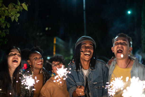 Friends celebrating with sparkers in the street at night Friends celebrating with sparkers in the street at night new year urban scene horizontal people stock pictures, royalty-free photos & images